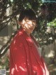 A woman in a red coat standing in front of a tree.