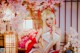 A woman in a white and red outfit sitting under a cherry blossom tree.