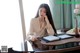 A woman sitting at a table with a laptop and a pen.