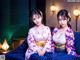 Two women in kimonos sitting on a blue couch.