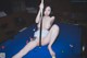 A naked woman sitting on a pool table holding a cue.