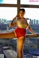 A woman in a red and white bathing suit posing by a window.