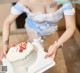 A woman in a blue and white dress holding a white cake.