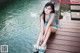 A woman in a blue bikini sitting on a wooden dock.