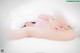 A woman laying on a bed under a white sheet.