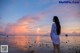 A woman standing on a beach looking out at the ocean.