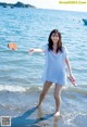 A woman in a white dress standing on a beach.