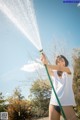 A woman holding a hose with water coming out of it.