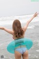 A woman in a bikini standing in the ocean with an inflatable ring.