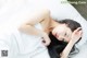 A woman laying on a bed with her hands on her head.