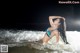 A woman in a blue bikini laying in the ocean.